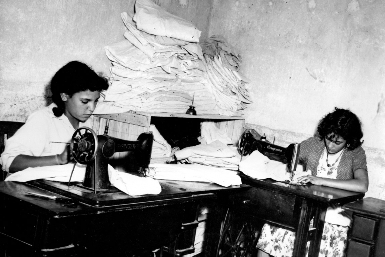 Two women work at sewing machines.