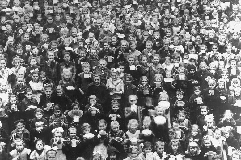Enormous crowd of children holding bowls.