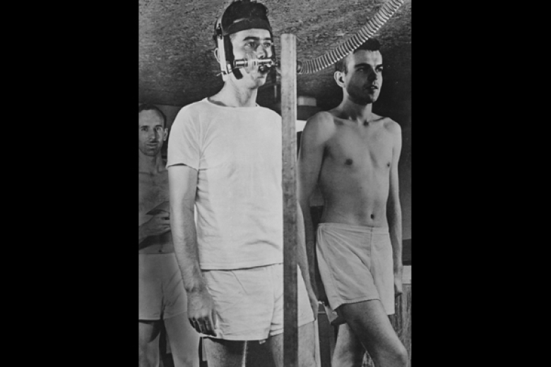 Young adult men standing, one with a tube and equipment attached to his head