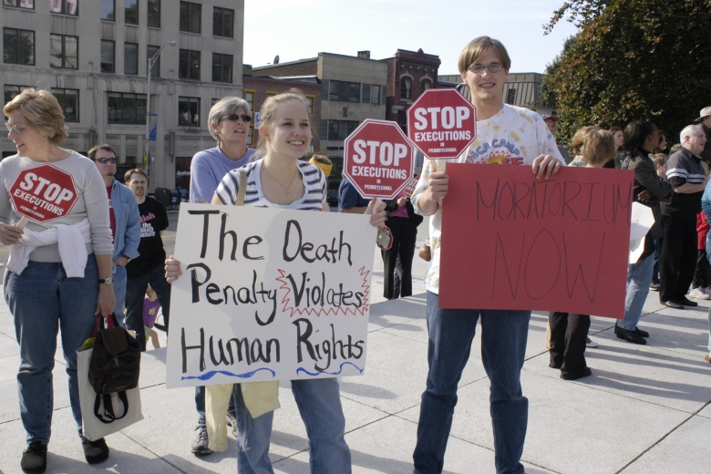 Demonstrators holding stop signs and other signs about ending the death penalty.