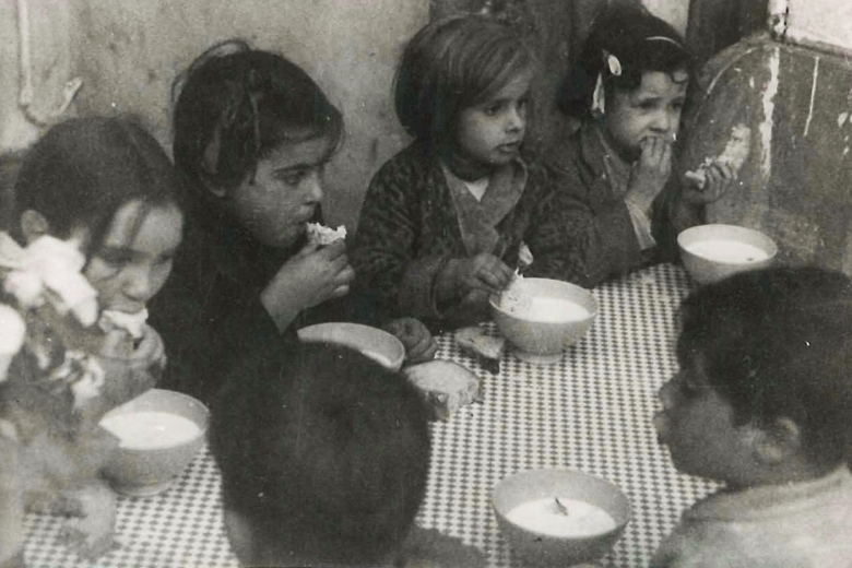 Children sitting at a table eating soup.