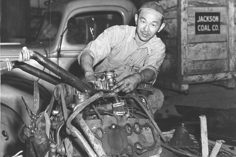 Man works on the mechanics of an engine