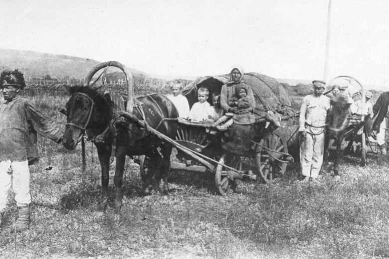 Horse-drawn wagon with men, women, children.