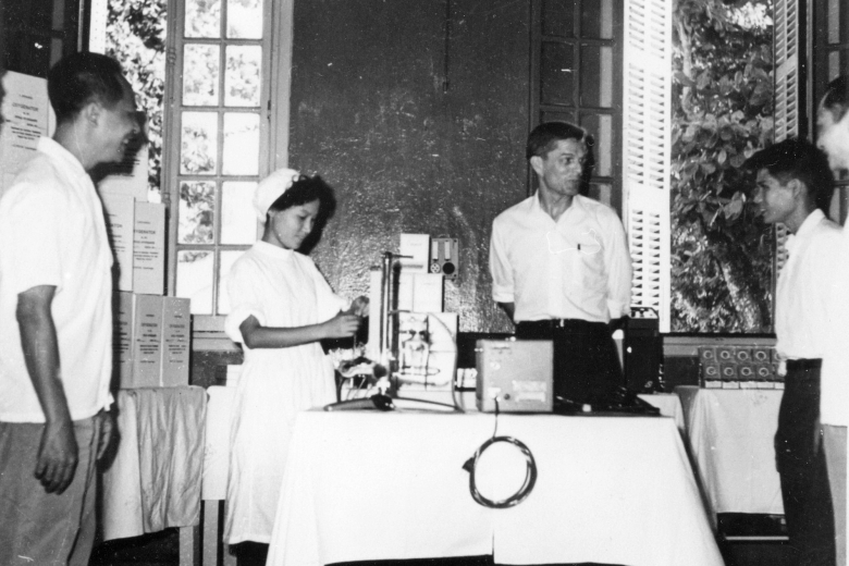Four people stand together near a table covered with medical equipment.