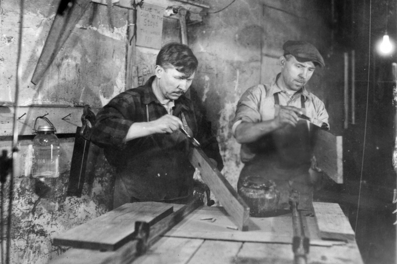 Two men in a workshop do woodworking
