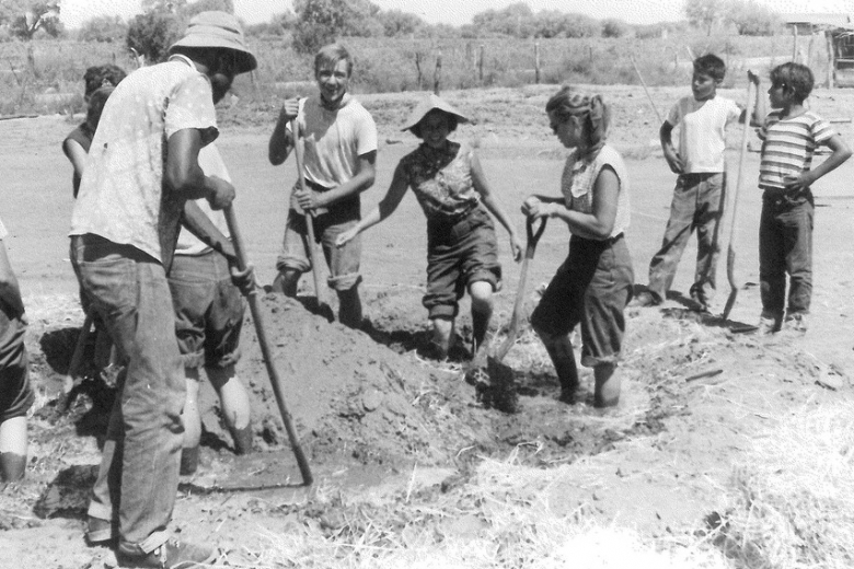 A group of people digs in clay soil