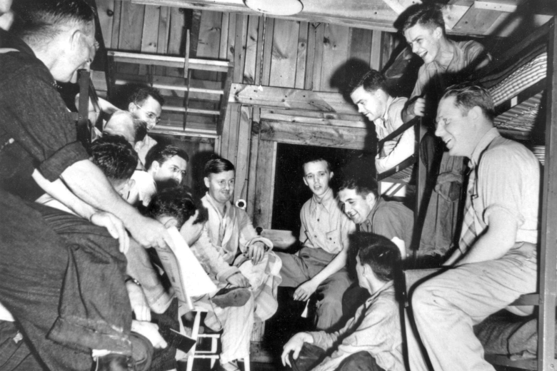 Group of young men talking and laughing inside a wooden building