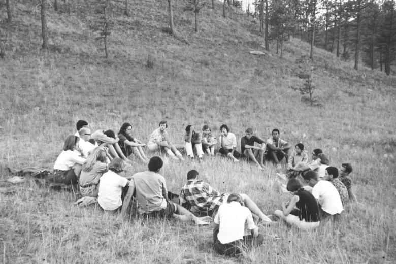 large circle of young men and women in meadow
