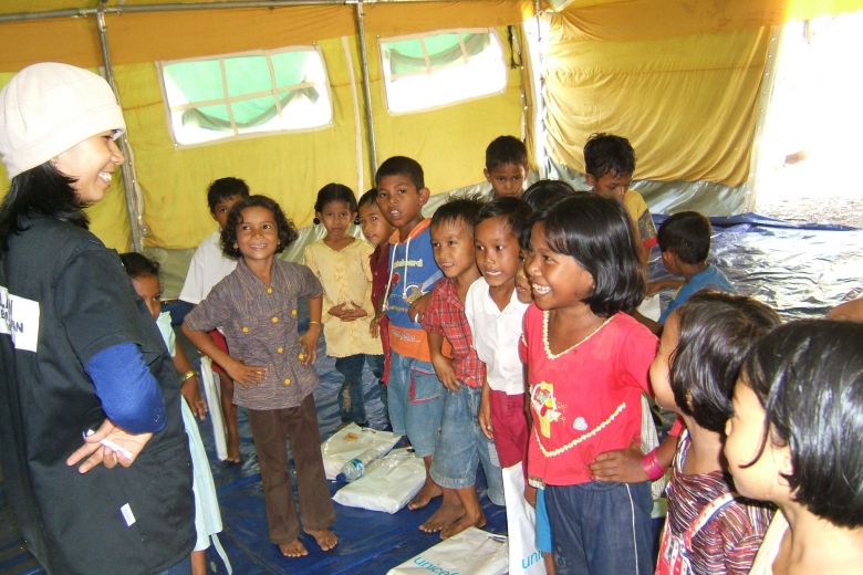 Children and teacher stand facing each other, hands on hips.