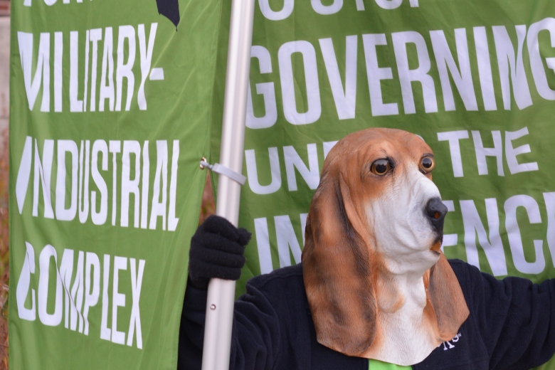 Person wearing dog mask holding a banner.