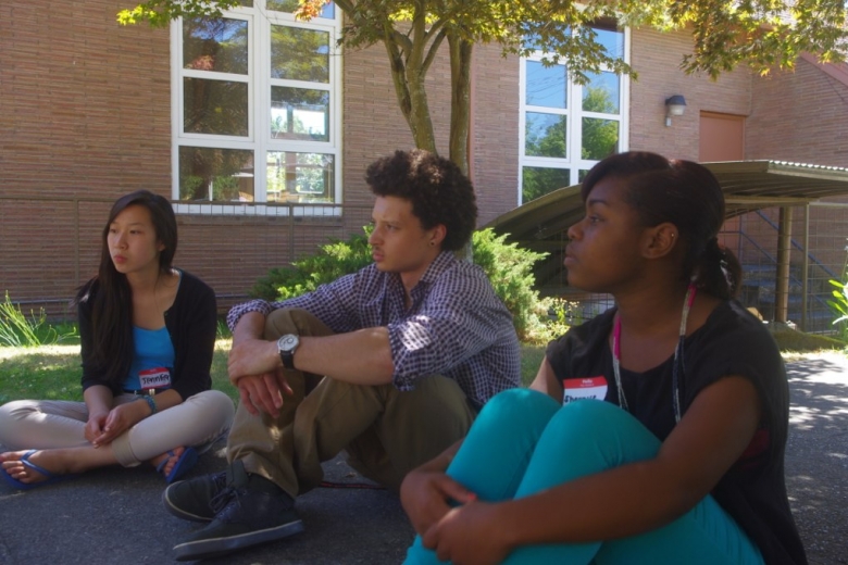 Three young people sit on the ground together.