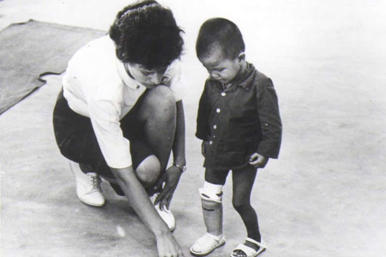 Woman crouching down next to a child with a prosthetic leg.