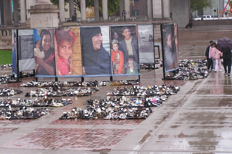 Collections of civilian shoes fill the space in front of large photos of Iraqis who had been killed in the war.