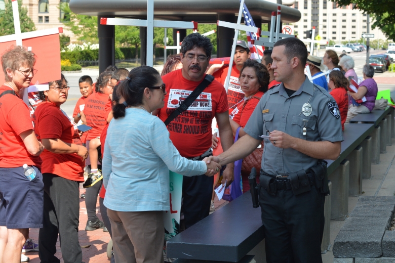 Surrounded by other protesters, a woman shakes hands with a police officer.