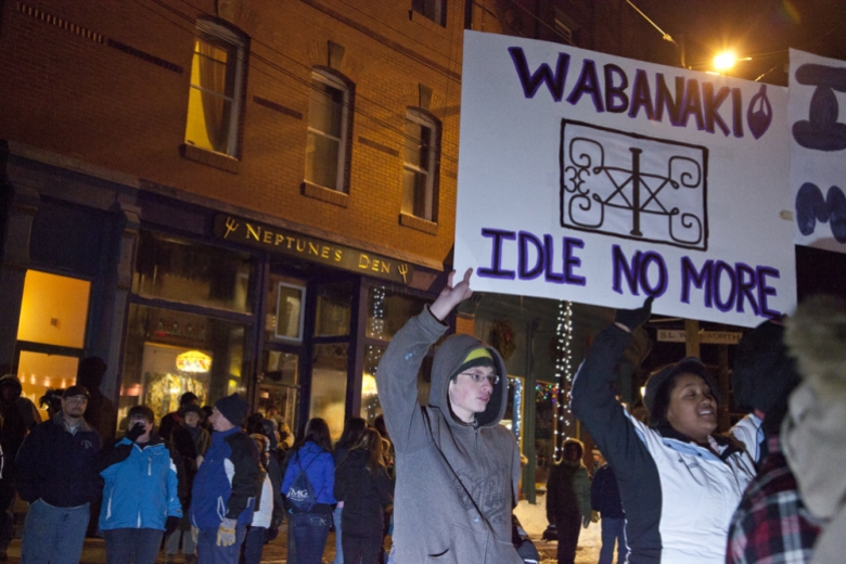Two people hold a sign that reads "Wabanaki Idle No More"